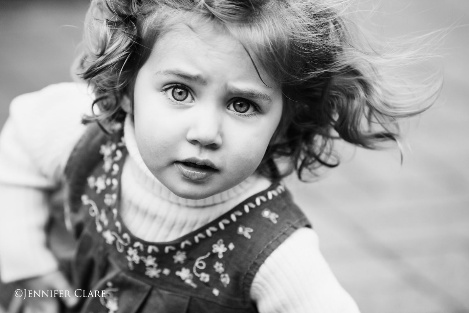a black and white image of a small girl with a quizzical expression.